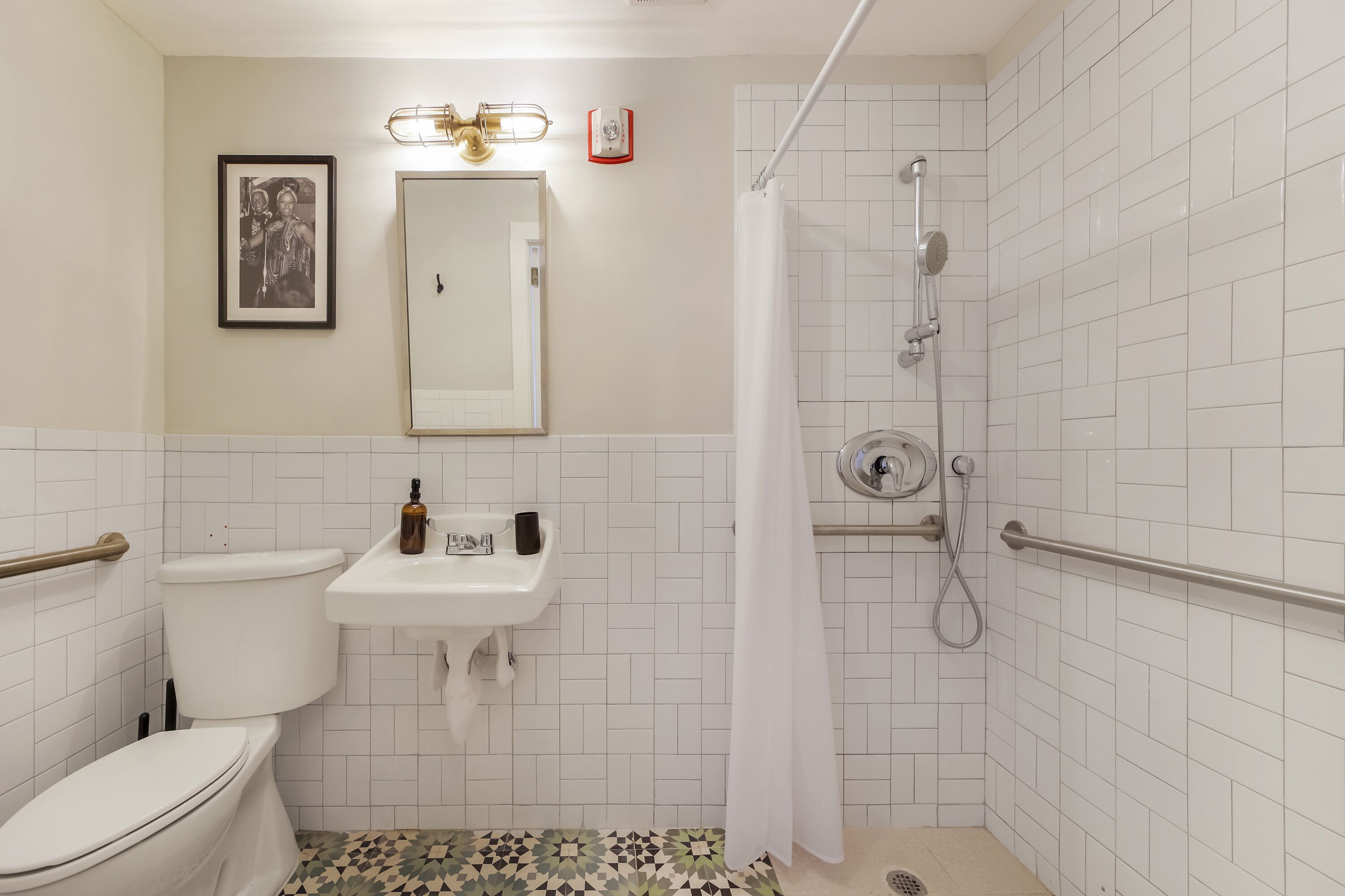 Une salle de bain comprenant des toilettes, un lavabo, une douche et un sol carrelé.