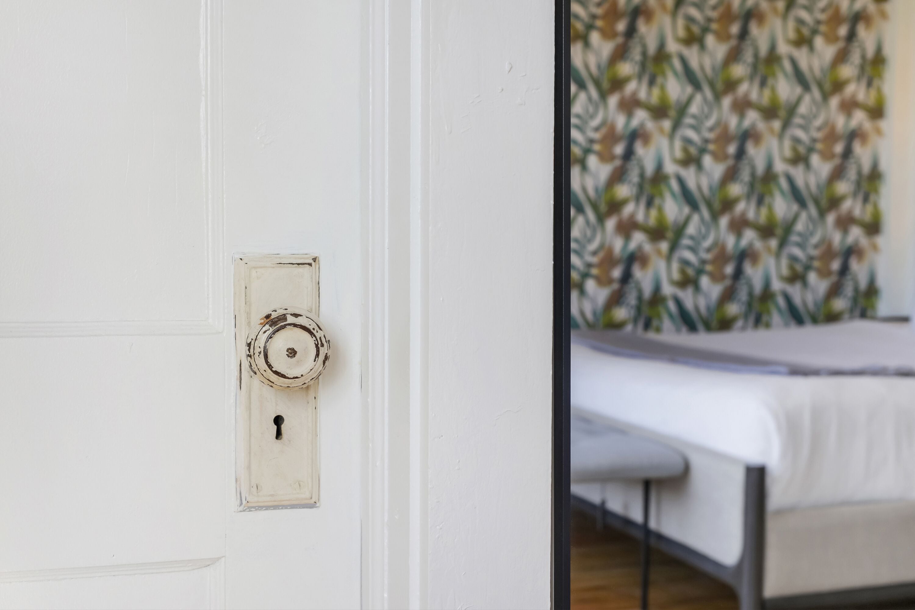 A white door with a keyhole and a patterned wallpaper in the background.