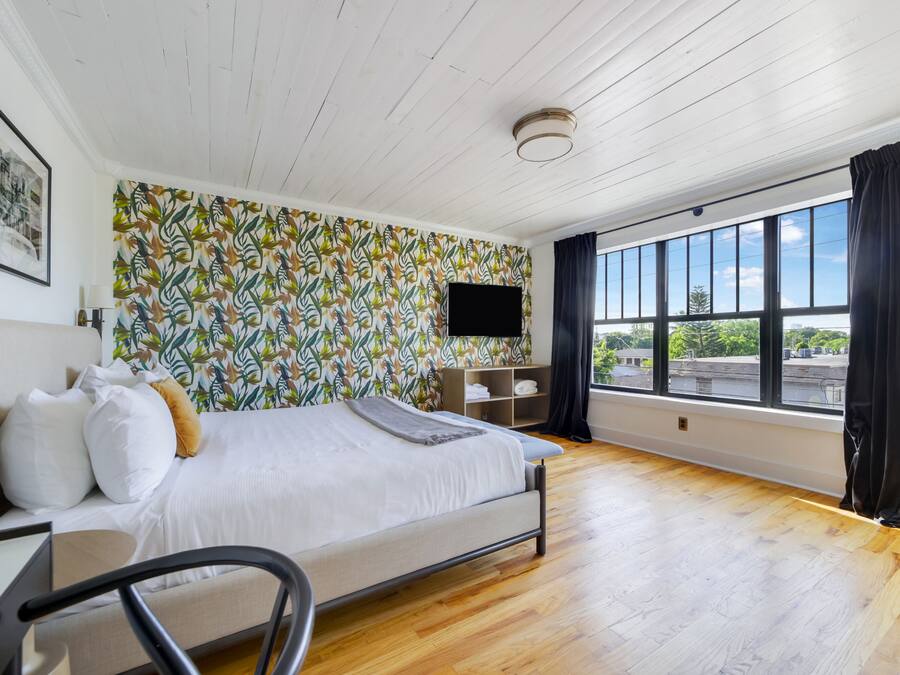 Ein Schlafzimmer mit einem Bett, einem Schreibtisch, einem Stuhl, einem Fernseher und einem Fenster mit Blick.