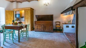 Een landelijke keuken met een zichtbare bakstenen plafond, houten kastjes en een eethoek met een tafel en stoelen.
