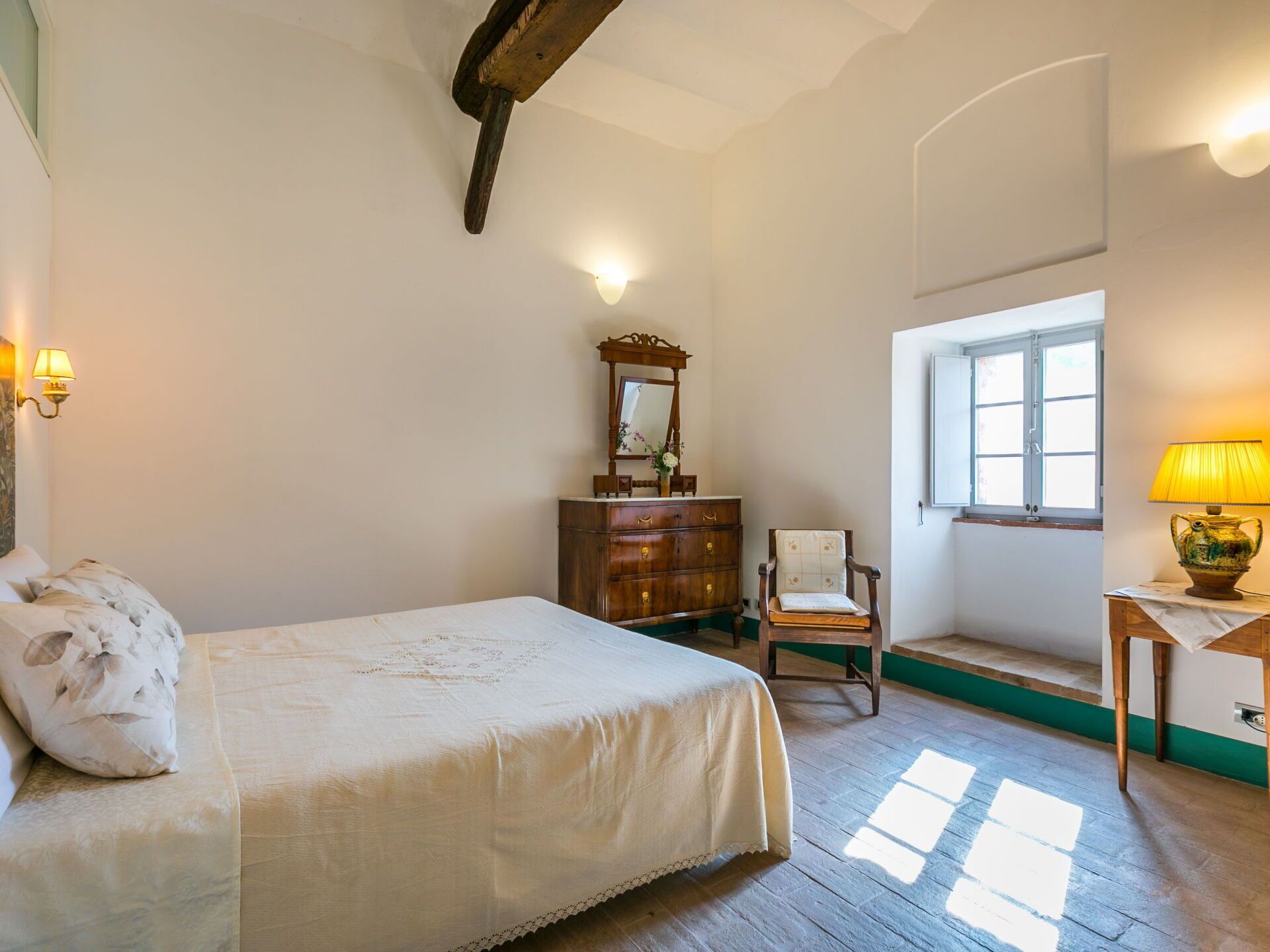 Une chambre à coucher comprenant un lit, une commode, une chaise et une fenêtre donnant sur un beau paysage.