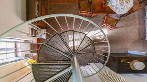 Una escalera de caracol con detalles de madera, un comedor con una mesa dispuesta para cuatro personas y vistas del piso superior.