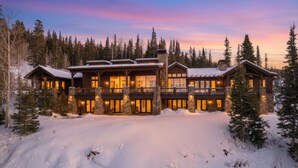 A large, multi-story lodge with a stone facade and large windows, surrounded by snow and trees. - Luxury & Modern Mountain Chalet in The Colony (Park City)