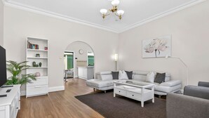 A modern living room with a white sofa, a coffee table, a bookshelf, and a TV.