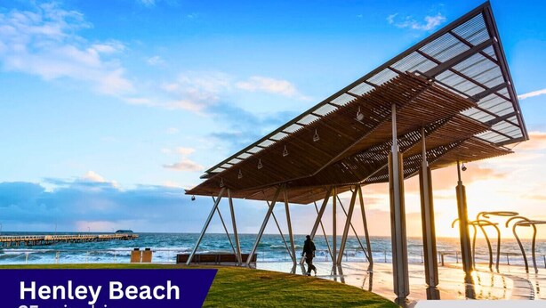 A beach pavilion with a metal roof and wooden beams, overlooking the ocean.