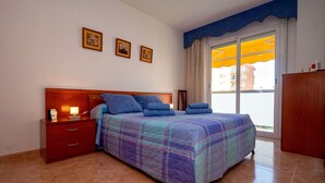 A bedroom with a bed, a nightstand, a wooden dresser, and a window with curtains. - Lovely apartment for 4 people with WIFI, pool, A/C, TV and balcony (Santa Susanna)