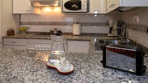 A kitchen with white cabinets, a microwave, a toaster, and a granite countertop. - Lovely apartment for 4 people with WIFI, pool, A/C, TV and balcony (Santa Susanna)