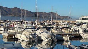 A marina with numerous boats docked, a bar/restaurant building, and mountains in the background. - Appartement DE 1 Chambre (Llançà)