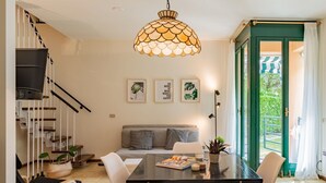 Une cuisine moderne avec une table à manger, des chaises, un luminaire suspendu et un escalier.