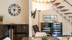 Un espace repas moderne avec une table en bois, des chaises, une plante en pot, des bougies et une horloge au mur.