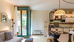 Un appartement moderne comprenant un salon, un coin repas et une cuisine. On y trouve un canapé, une table à manger, des chaises et un comptoir de cuisine.
