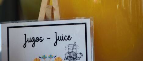 A glass container labeled 'Jugos - Juice' with a wooden clothespin on it.