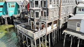 Een meerlaags houten gebouw met balkons, boven water gebouwd, met een combinatie van open en afgesloten ruimtes.