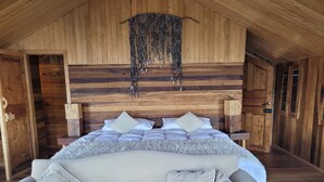 Een knus slaapkamer met een houten plafond, een groot bed met wit beddengoed en een bank met bijpassende kussens.