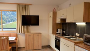 Cocina moderna con televisor de pantalla plana, armarios de madera, horno empotrado y lavavajillas.