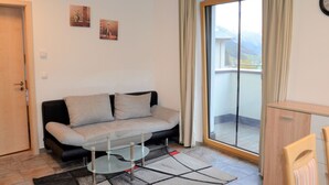 Una sala de estar moderna con un sofá, una mesa de centro de vidrio y vistas a un balcón.