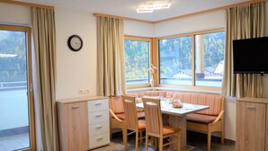 Una habitación de esquina con una mesa de comedor, sillas, un reloj y un televisor.