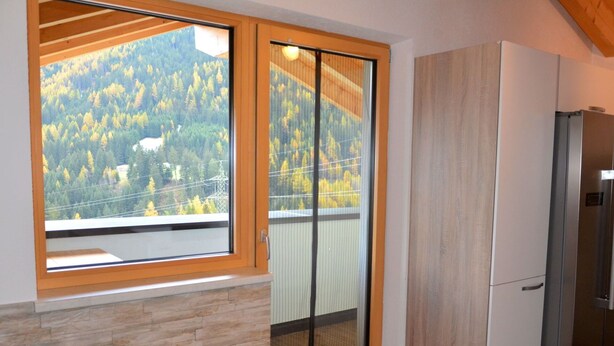 Una cocina con un ventanal amplio, armarios de madera y un refrigerador empotrado.