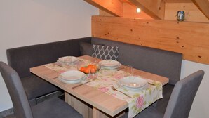 Comedor con una mesa de madera dispuesta para cuatro personas, rodeado de sillas tapizadas en gris.