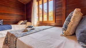A cozy cabin room with wooden walls and a large window. There are two beds with patterned bedding and a small table with a decorative item. - Stunning private villa for 6 people with WIFI, A/C, private pool, TV, patio and pets allowed (Deltebre)