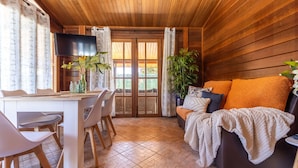 A cozy room with wooden walls, a dining table with chairs, a sofa with cushions, and a television on the wall. - Stunning private villa for 6 people with WIFI, A/C, private pool, TV, patio and pets allowed (Deltebre)