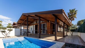 Ett modernt hus med en täckt uteplats, en swimmingpool och en trädgård.
