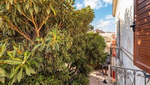 Un balcon donnant sur un paysage urbain, une rambarde en métal et un bâtiment avec une porte en bois.
