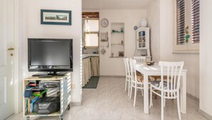 Un espace de vie compact comprenant un téléviseur, une petite table à manger et un coin cuisine.