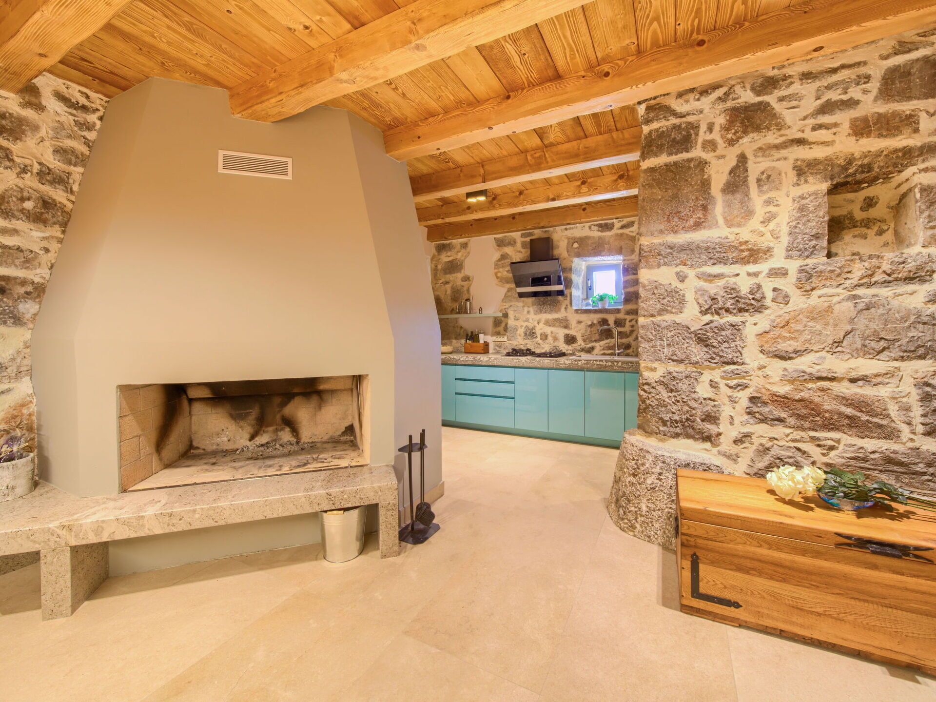 Uma cozinha rústica com parede de pedra, forno embutido e teto de madeira.