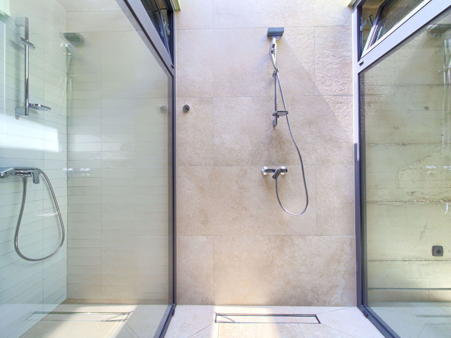A glass-enclosed shower area with a handheld showerhead and a fixed showerhead.