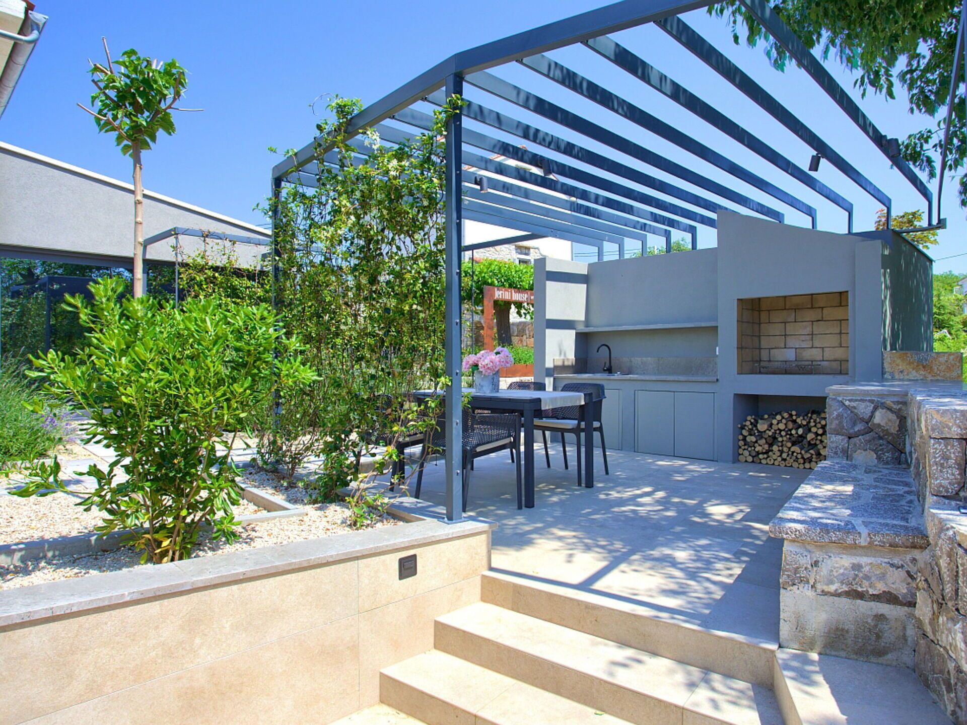 An outdoor kitchen area with a grill, dining table, and chairs.