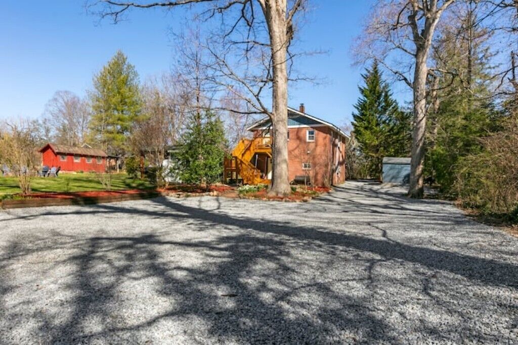 A gravel driveway leading to a red brick building with a yellow staircase.