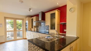 Une cuisine moderne avec un plan de travail noir, des armoires en bois, un pare-feu en carrelage et un mur d’accent rouge.