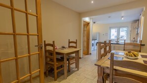 Un coin repas avec des meubles en bois, une cuisine à l’arrière-plan et une buanderie.
