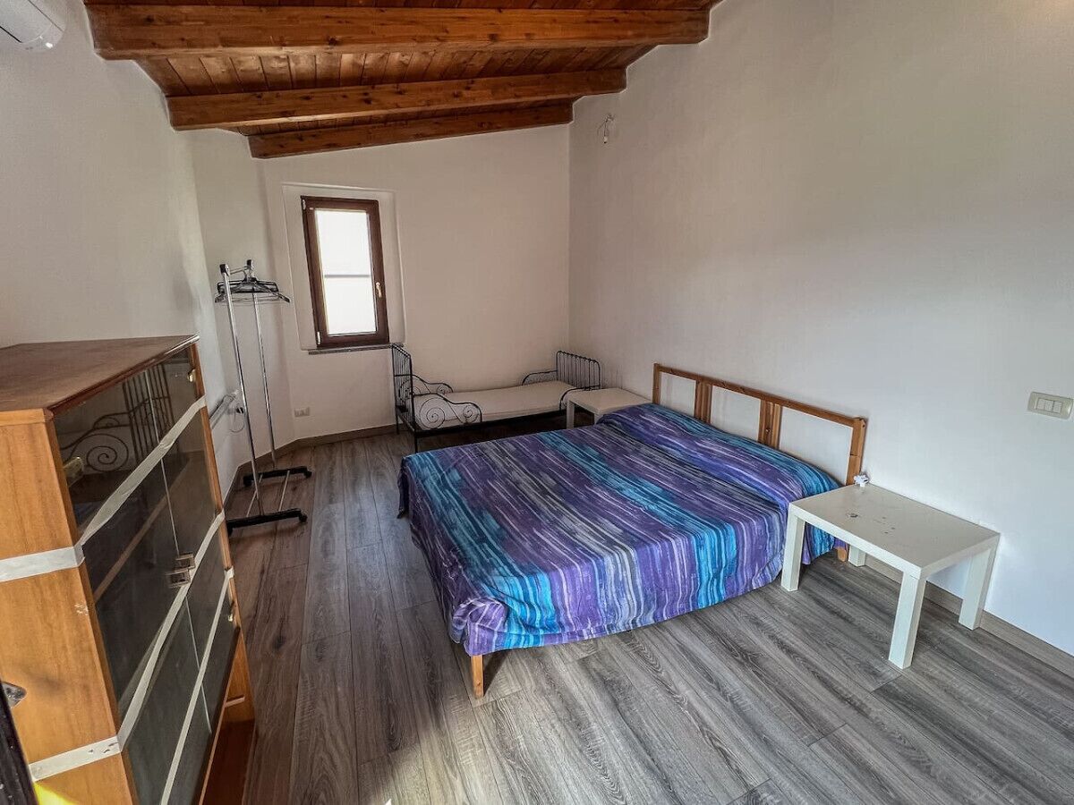 Une chambre avec un plafond en bois, un lit recouvert d’une courtepointe aux couleurs vives, une petite table et une fenêtre.