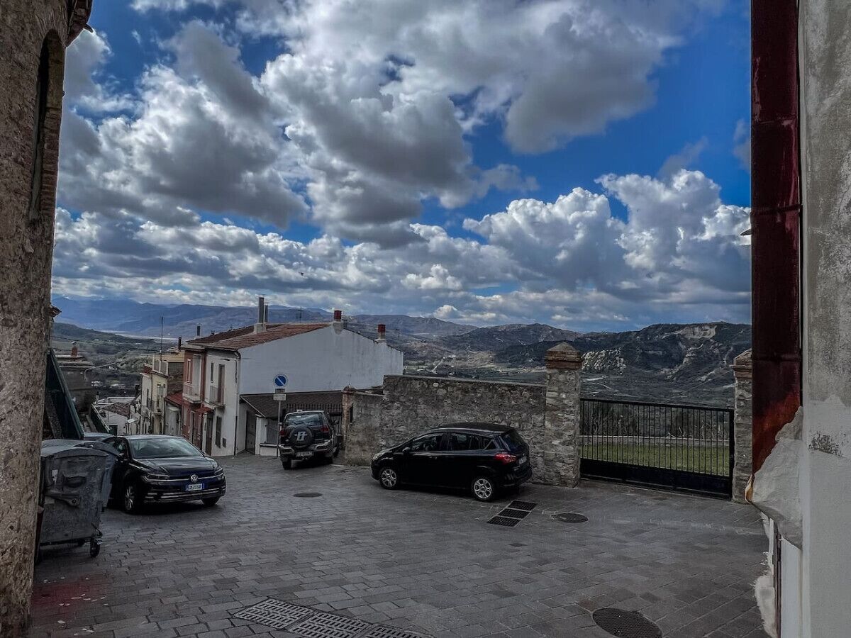 A courtyard with parked cars and a view of mountains.
