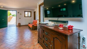 Ein geräumiges Zimmer mit einem Holzschrank, einem großen Spiegel und einem Fernseher. Ein Stuhl und ein kleiner Tisch mit Geschirr sind ebenfalls vorhanden.