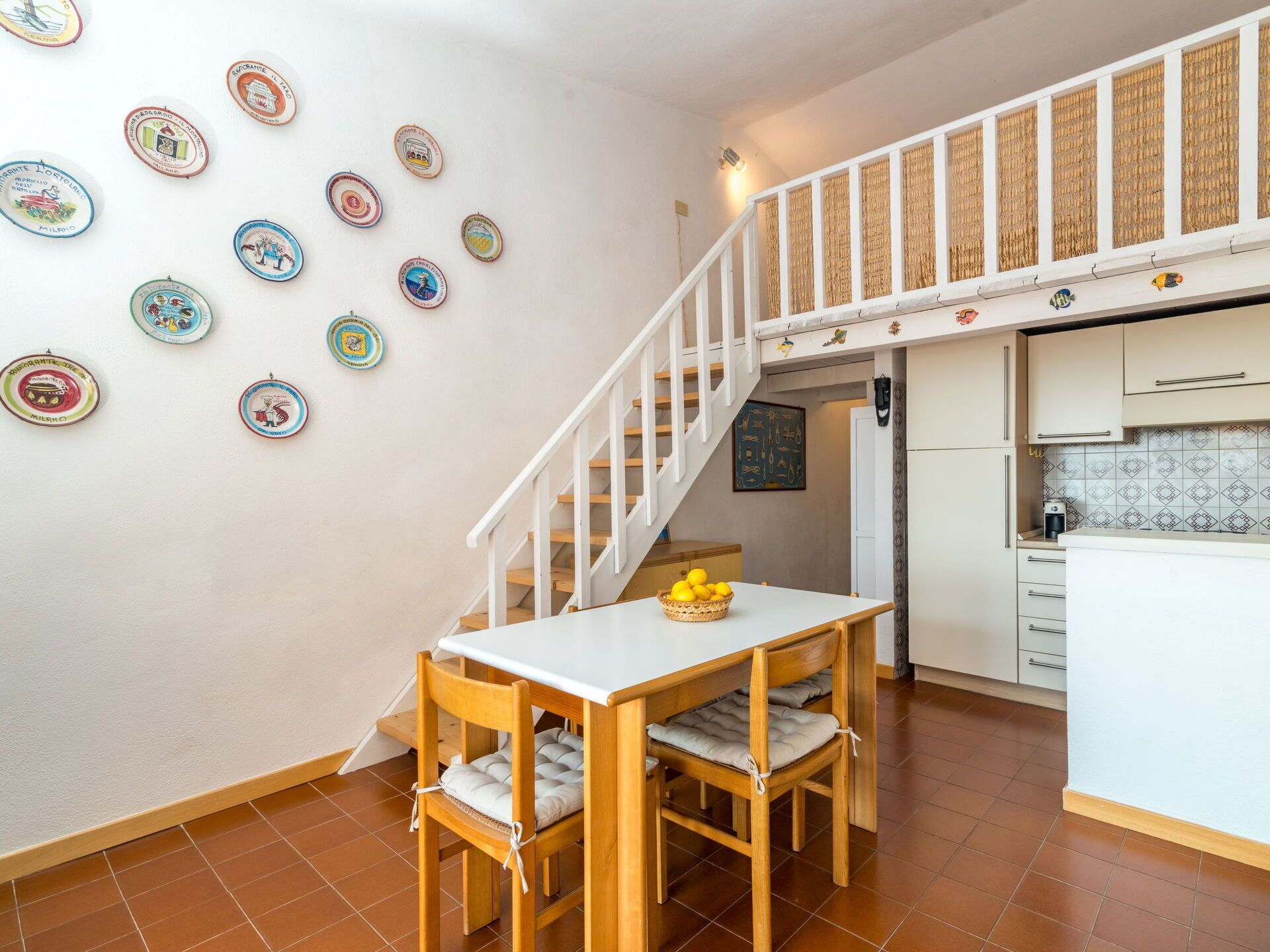 A kitchen with a dining area, a staircase, and decorative plates on the wall.