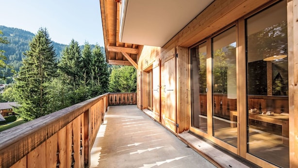 Ein Holzbalkon mit Blick auf einen Wald und Berge.