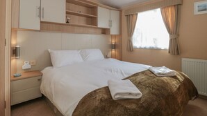 Une chambre à coucher avec un lit, des tables de chevet, une armoire et une fenêtre avec des rideaux.