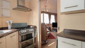 Une cuisine compacte équipée d’une cuisinière, d’un four et d’un coin repas avec un téléviseur.