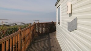 Une terrasse en bois mène à un bâtiment blanc doté d'une fenêtre et d'une enseigne.