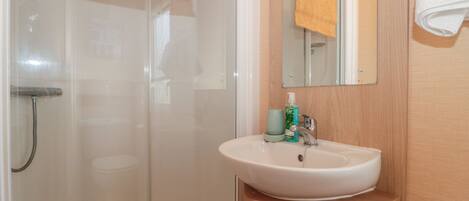 Un baño con cabina de ducha de vidrio, un lavabo con espejo y un mueble de madera debajo.