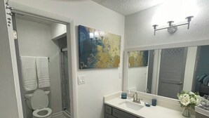 Un baño con inodoro, ducha, lavabo y espejo.