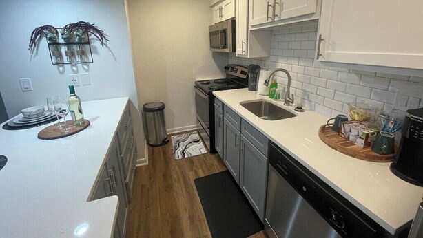 Una cocina moderna con armarios blancos, electrodomésticos de acero inoxidable y encimera negra.
