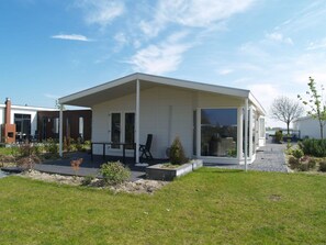 Relax in the covered patio area, surrounded by lush plants and a well-maintained lawn.