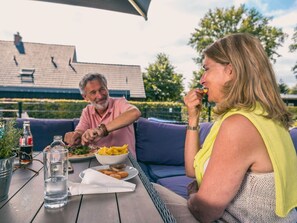 Enjoy a romantic meal for two in this serene outdoor dining area, complete with a table set and a beautiful potted plant.