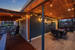 Un espace extérieur abrité, doté d'un plancher en bois, de chaises en métal et d'un panneau néon sur lequel on peut lire : « Nashville Music Club ».