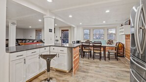 A modern kitchen with white cabinetry, a central island, and a stainless steel refrigerator.