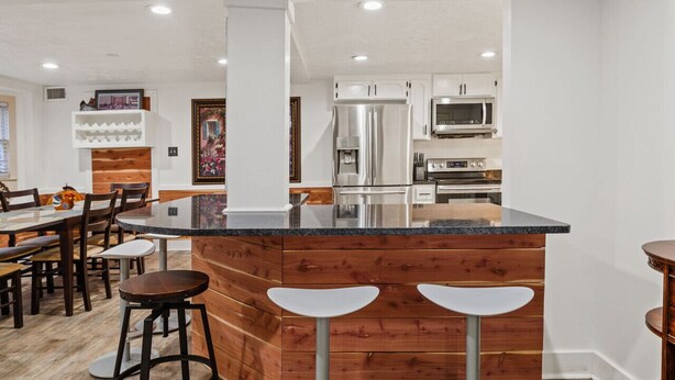 A modern kitchen with a central island, white cabinetry, and stainless steel appliances.
